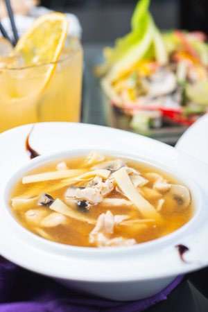 Traditional soup with meat broth in a white plate on a table in a restaurant. Complete and varied food. Soft focus and beautiful bokeh. Complex lunch.の写真素材