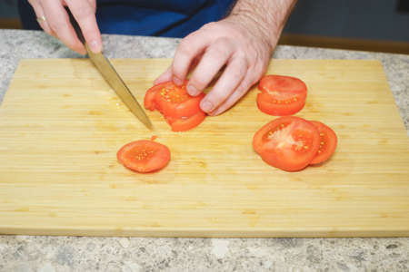 Process of cooking in the kitchen close-up: hands of a cook with a knife and vegetables.の写真素材