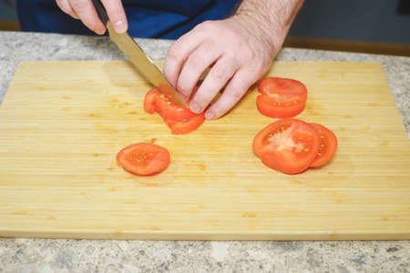 Process of cooking in the kitchen close-up: hands of a cook with a knife and vegetables.の写真素材