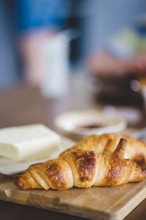 Cozy homemade breakfast: a couple of croissants on a wooden boardの写真素材