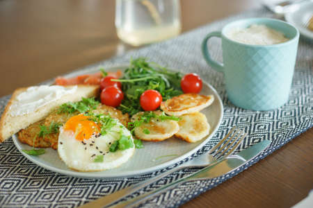 Cozy homemade breakfast: potato pancakes with scrambled eggs, red fish, cheese and vegetables with herbsの写真素材