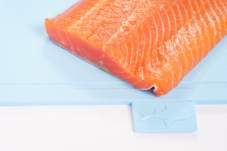 Fillet of red fish on a blue plastic cutting board.の写真素材