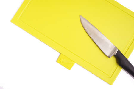 Bright green yellow clean plastic cutting board with a kitchen knife on a white background.の写真素材