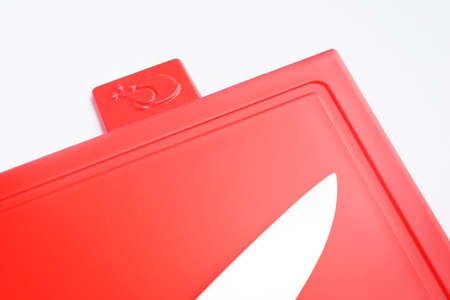 Bright red clean plastic cutting board with a kitchen knife on a white background.の写真素材