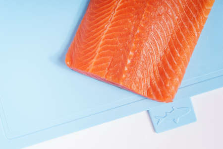 Fillet of red fish on a blue plastic cutting board.の写真素材