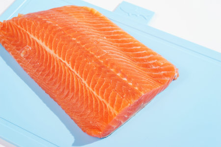 Fillet of red fish on a blue plastic cutting board.