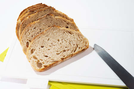 Pieces of bread on a cutting board top view on white clean plastic cutting boardの写真素材