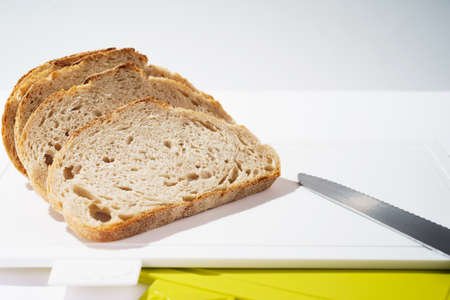 Pieces of bread on a cutting board top view on white clean plastic cutting boardの写真素材