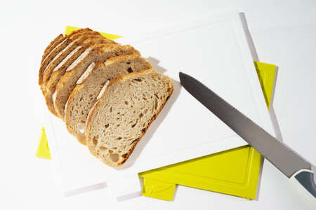 Pieces of bread on a cutting board top view on white clean plastic cutting boardの写真素材