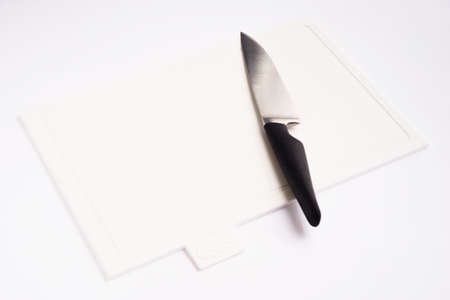 Bright white clean plastic cutting board with a kitchen knife on a white background.の写真素材