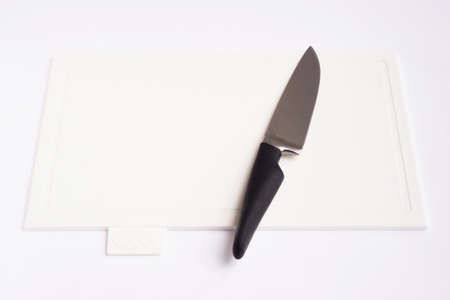 Bright white clean plastic cutting board with a kitchen knife on a white background.の写真素材