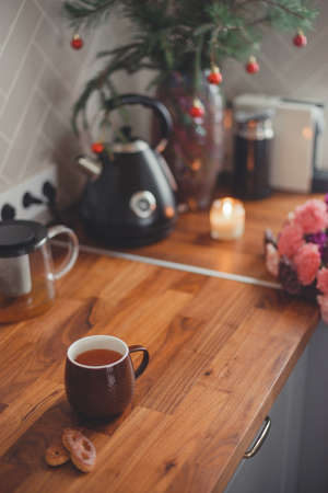 Cozy home lifestyle: a cup of tea with cookies on a wooden table top with beautiful carnation flowersの写真素材