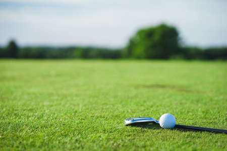 Golf ball and putter on the green grass next to the hole.の写真素材