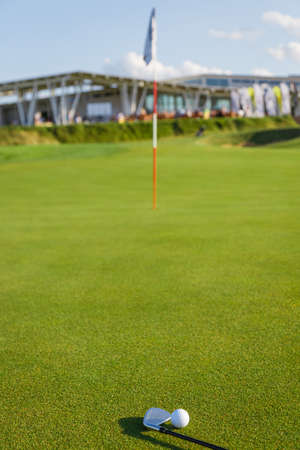 Golf ball and putter on the green grass next to the hole.の写真素材