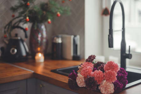 Cozy home lifestyle: wooden table top with beautiful carnation flowers and Christmas decorations.の写真素材