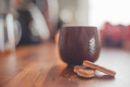 Cozy home lifestyle: a cup of tea with cookies on a wooden table top with beautiful carnation flowersの写真素材