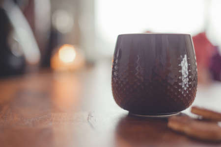 Cozy home lifestyle: a cup of tea with cookies on a wooden table top with beautiful carnation flowersの写真素材
