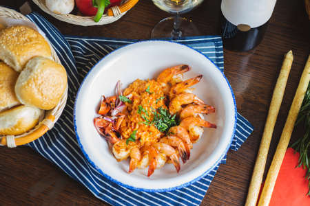 Traditional bright shrimp risotto in a bowl on a table in a restaurant with a beautiful decor in a dark key close-up.の写真素材