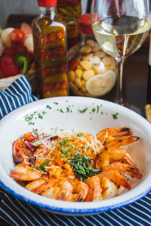 Traditional bright shrimp risotto in a bowl on a table in a restaurant with a beautiful decor in a dark key close-up. Soft focus, beautiful bokeh and stylish toning.の写真素材