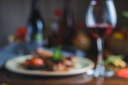 Blurred Fried ribs with a glass of red wine on a table in a restaurant close-up, in a dark key. Content for the promotion of the cafe. Soft focus and stylish toning.の写真素材