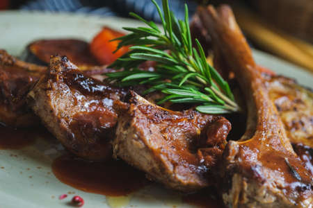 Fried ribs with a glass of red wine on a table in a restaurant close-up, in a dark key. Content for the promotion of the cafe. Soft focus and stylish toning.の写真素材