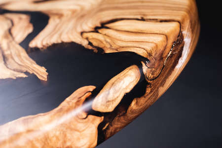 Slab and round wooden table top with plastic decorative inserts, saw cut wood treated varnish close-up on a black background. Isolate. Luxury wood for countertops and tables. Design materials, detailsの写真素材