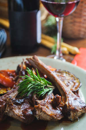 Fried ribs with a glass of red wine on a table in a restaurant close-up, in a dark key. Content for the promotion of the cafe. Soft focus and stylish toning.の写真素材