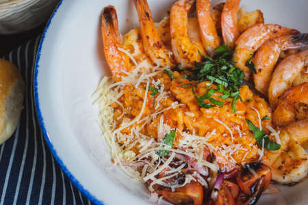 Traditional bright shrimp risotto in a bowl on a table in a restaurant with a beautiful decor in a dark key close-up. Soft focus, beautiful bokeh and stylish toning.の写真素材