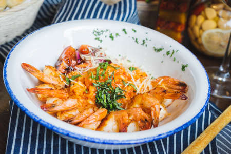 Traditional bright shrimp risotto in a bowl on a table in a restaurant with a beautiful decor in a dark key close-up. Soft focus, beautiful bokeh and stylish toning.の写真素材
