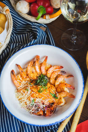 Traditional bright shrimp risotto in a bowl on a table in a restaurant with a beautiful decor in a dark key close-up. Soft focus, beautiful bokeh and stylish toning.の写真素材