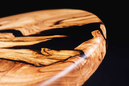 Slab and round wooden table top with plastic decorative inserts, saw cut wood treated varnish close-up on a black background. Isolate. Luxury wood for countertops and tables. Design materials, detailsの写真素材