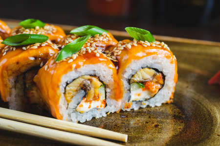 Traditional Japanese rolls with salmon fish, eel, seafood on a plate with wooden chopsticks, close-up and soft focus. Image photos for the menu of a Japanese restaurant, content for social networks.の写真素材