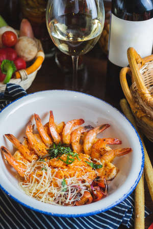 Traditional bright shrimp risotto in a bowl on a table in a restaurant with a beautiful decor in a dark key close-up. Soft focus, beautiful bokeh and stylish toning.の写真素材