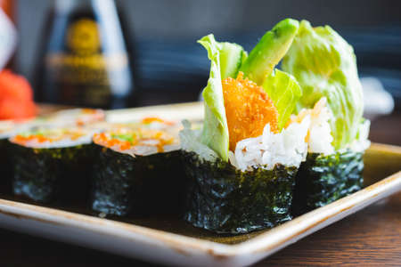 Traditional Japanese rolls with shrimps and vegetables on a plate with wooden chopsticks, close-up and soft focus. Image photos for the menu of a Japanese restaurant, content for social networks.の写真素材
