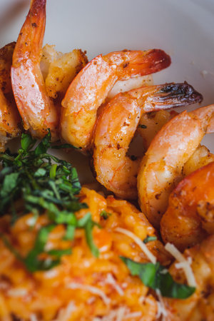Traditional bright shrimp risotto in a bowl on a table in a restaurant with a beautiful decor in a dark key close-up. Soft focus, beautiful bokeh and stylish toning.の写真素材