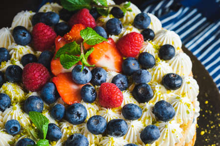 Honey layer cake with whipped cream, strawberries and blueberries on the table.の写真素材