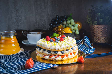 Honey layer cake with whipped cream, strawberries and blueberries on the table.の写真素材
