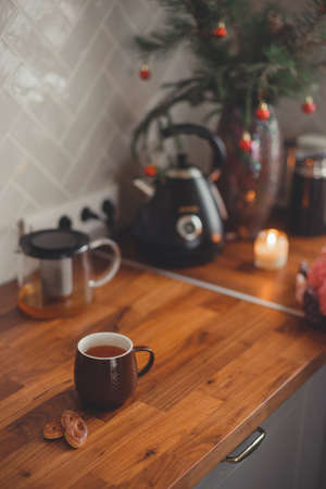 Cozy home lifestyle: a cup of tea with cookies on a wooden table top with beautiful carnation flowersの写真素材