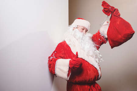 Santa Claus, man in a traditional red costume with bag of gifts on a white backgroundの写真素材