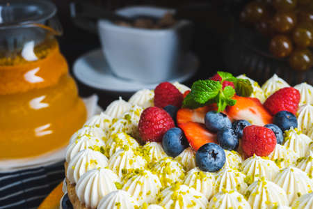Honey layer cake with whipped cream, strawberries and blueberries on the table.の写真素材