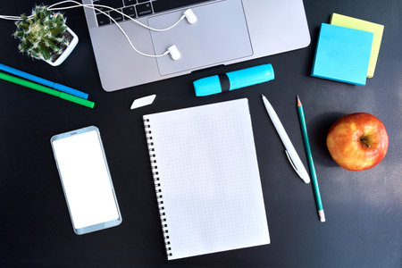 Workplace with laptop, notepad, earphones, apple and smartphone top view. Work from home. Remote...