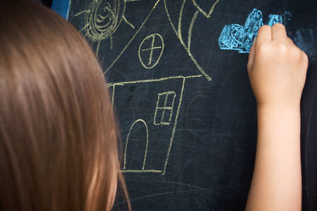 Little girl draws with chalk on the blackboard . The development of creativity. Drawing lessonの写真素材