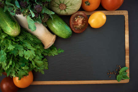 Vegetables dark background with copy space. Healthy meal. Menu, price background. Vegetables on black chalkboard.の写真素材