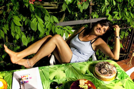romantic sexy  girl smiles on the terrace in front of two cakesの写真素材