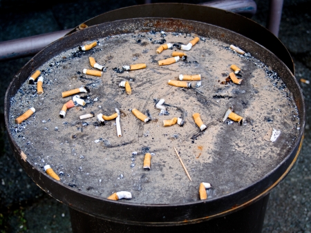 Cigarette butts in a container outdoor ashtrayの写真素材