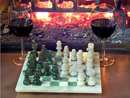play chess drinking red wine in front of a roaring fireplaceの写真素材