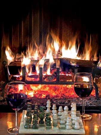 play chess drinking red wine in front of a roaring fireplaceの写真素材