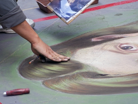 street artist paints with chalk on the pavementの写真素材