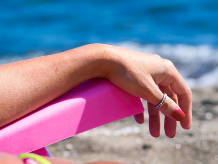 woman relaxes on a deck chair, on the beach, facing the seaの写真素材