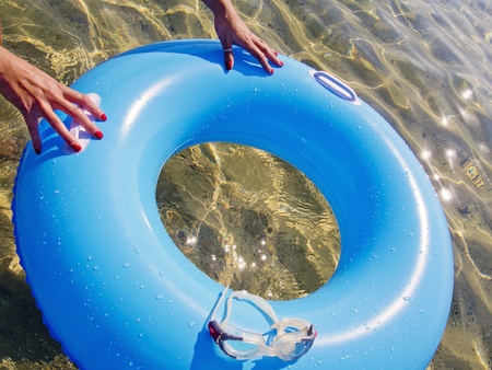 hands pushing a blue donut inflatable in the seaの写真素材
